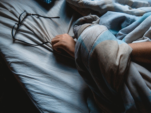 black framed eyeglasses on a blue bedsheet